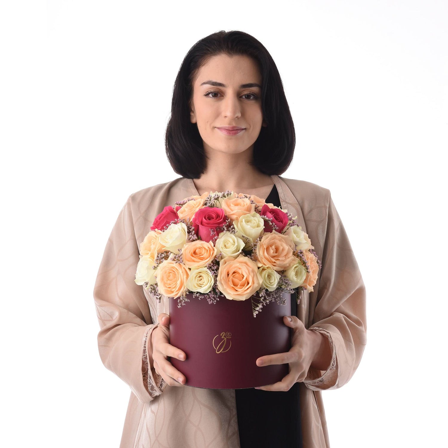 Woman holds burgundy hat box filled with vibrant peach, pink, and cream roses.
