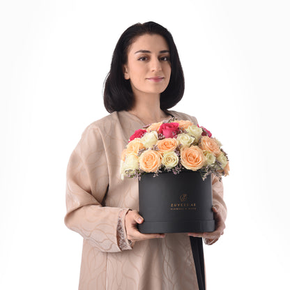 Elegant woman holds black box of vibrant multi-colored roses.