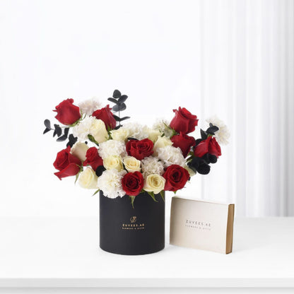 Elegant black box with red and white roses from, paired with fine chocolates of Zuvees Luxe Chocolate, Mirzam and Lakrids — a refined romantic gift.