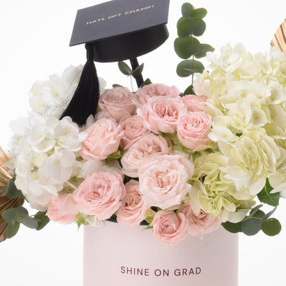 Pink roses and hydrangeas in box with graduation cap topper.