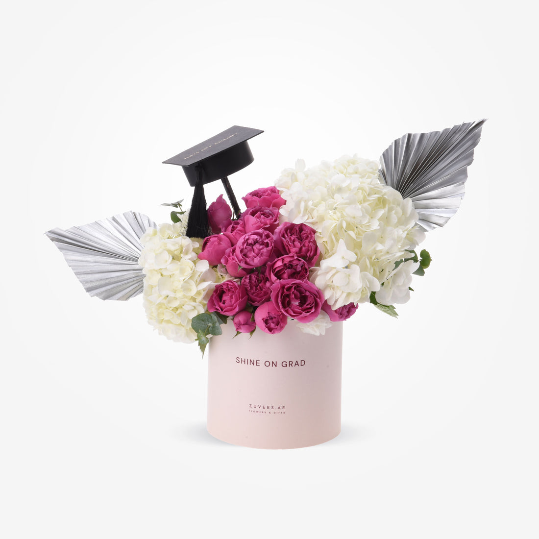 Pink cylinder holds vibrant pink roses and white hydrangeas, accented by silver wings and graduation cap.