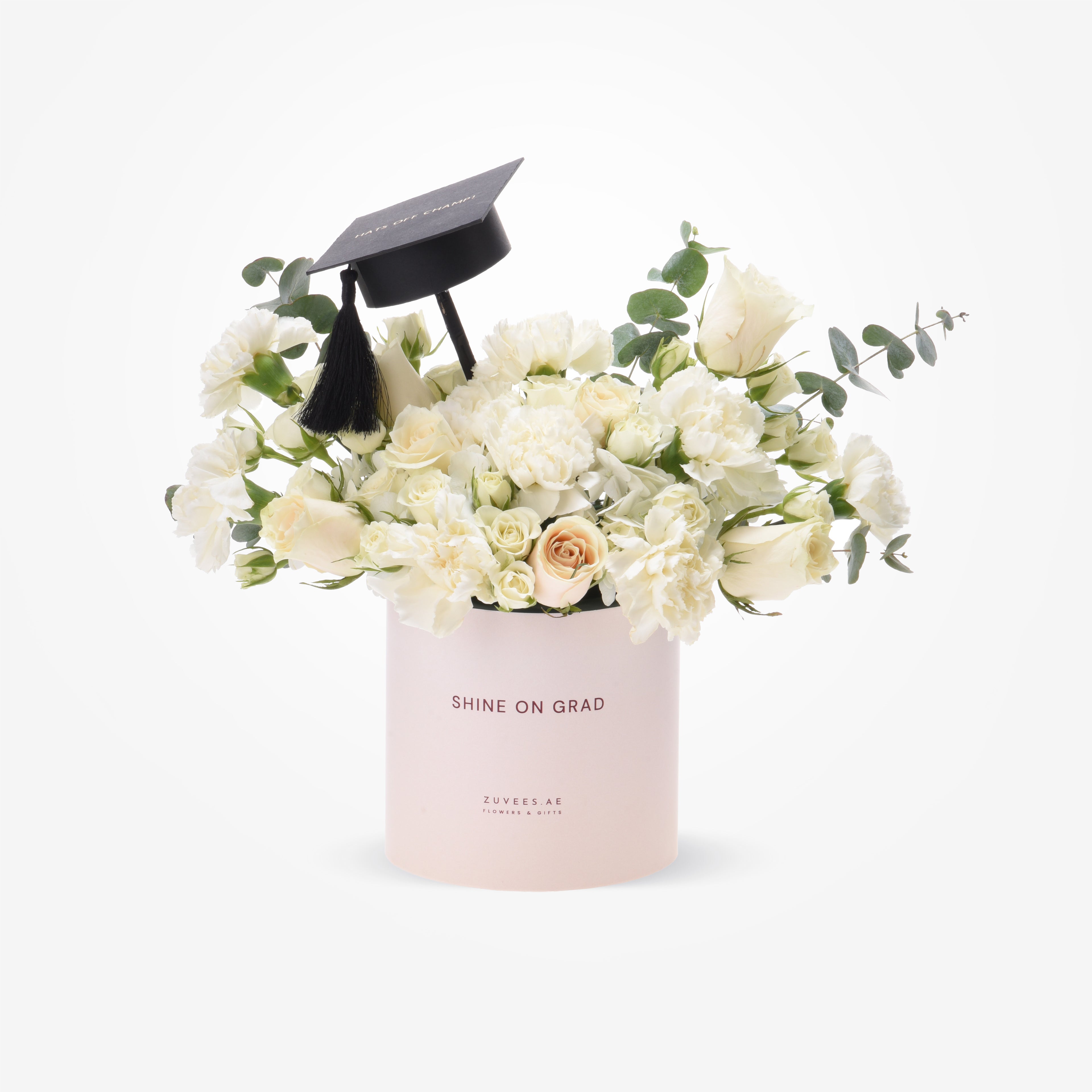 Elegant white roses and eucalyptus in blush box, topped with graduation cap.