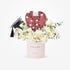Pink cylinder holds white roses, graduation cap, and heart-shaped gift box.