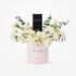 Elegant white roses and eucalyptus surround Dior Sauvage perfume in blush cylinder.
