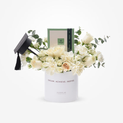 Elegant white floral graduation gift with mini cap and Patchi candle.