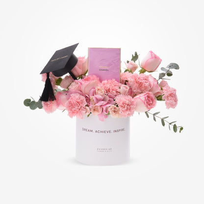 Pink roses and carnations in white cylinder with graduation cap and Chanel perfume.