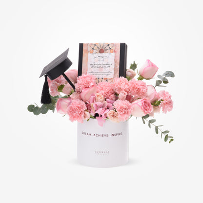 Pink floral graduation gift with "Dream. Achieve. Inspire." vase and chocolate box.