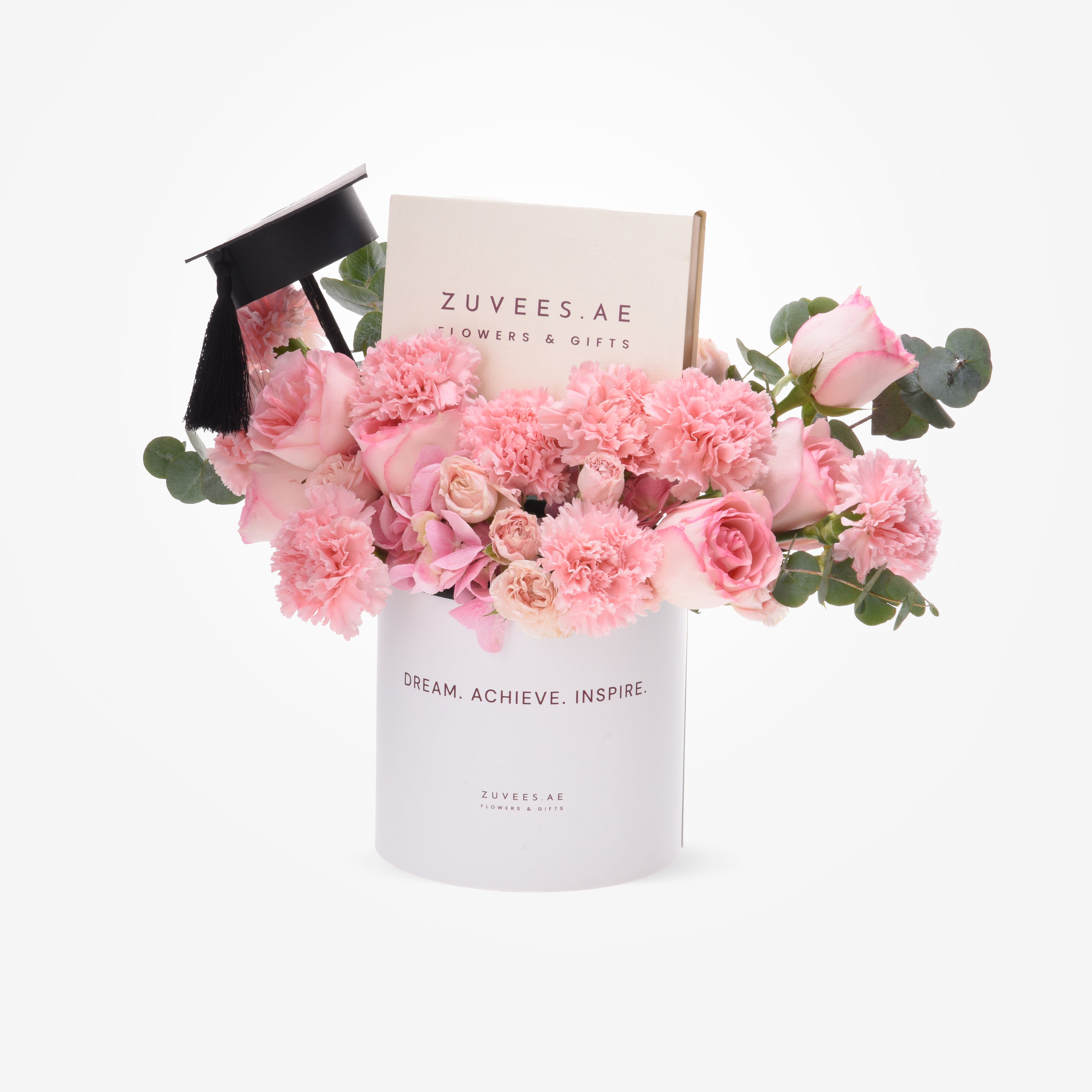 Pink roses and carnations in white cylinder with graduation cap and branded box.