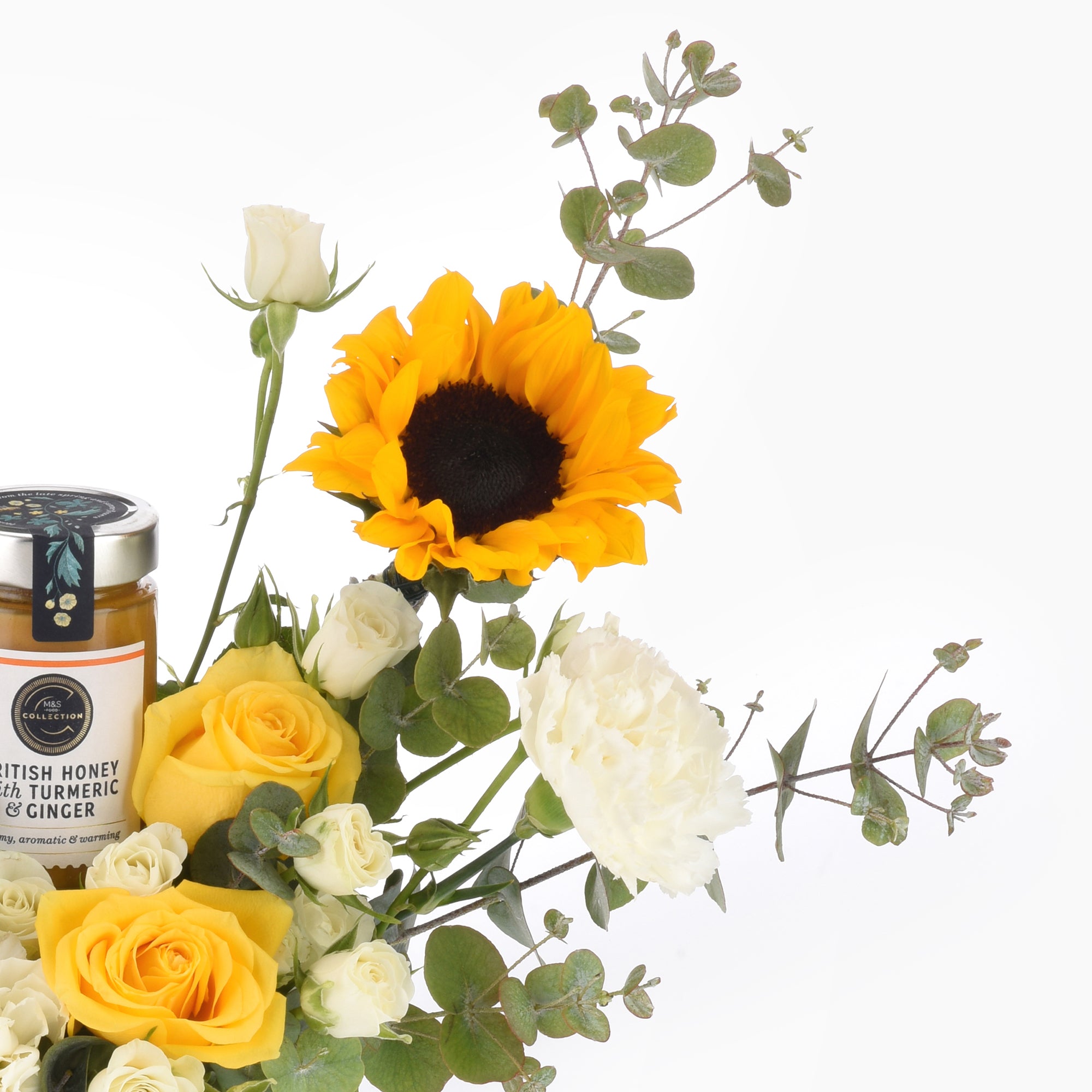 Vibrant sunflower, yellow and white roses, eucalyptus, and turmeric honey jar in elegant floral arrangement.