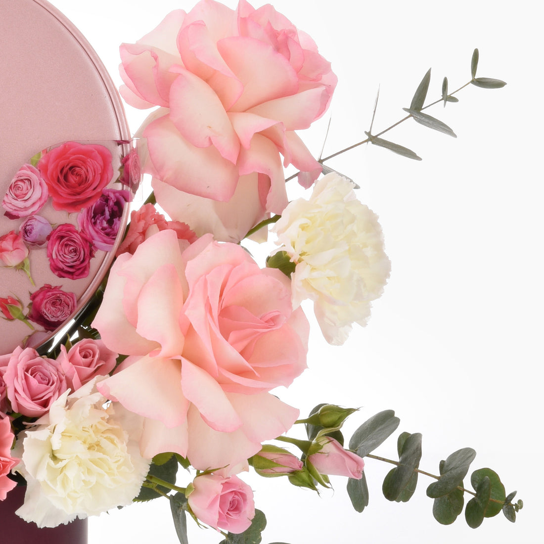 Soft pink roses and white carnations with eucalyptus, in rose-gold container.