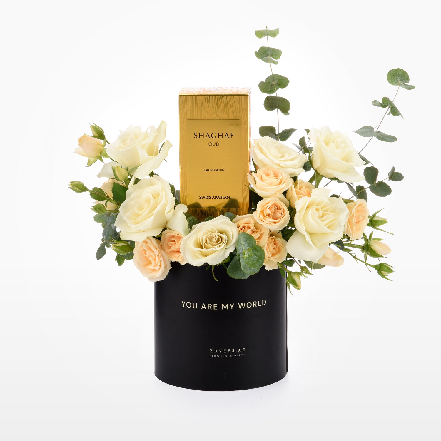 Elegant black vase with "You Are My World" text, holding cream roses and eucalyptus, centered with a gold Shaghaf Oud perfume box.