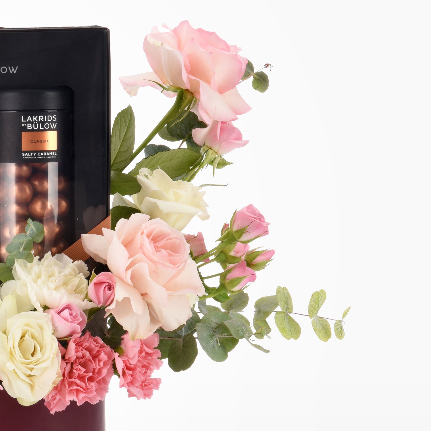 Soft pink, white roses and carnations with eucalyptus, beside black chocolate gift.