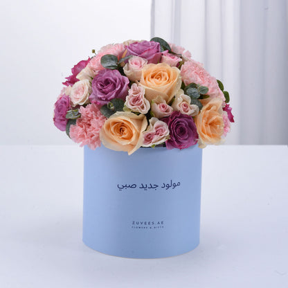 Pastel pink, purple, and peach roses in light blue box with Arabic birthday message.