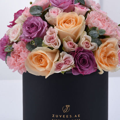 Luxurious pastel roses and carnations in sleek black box with dewdrops.