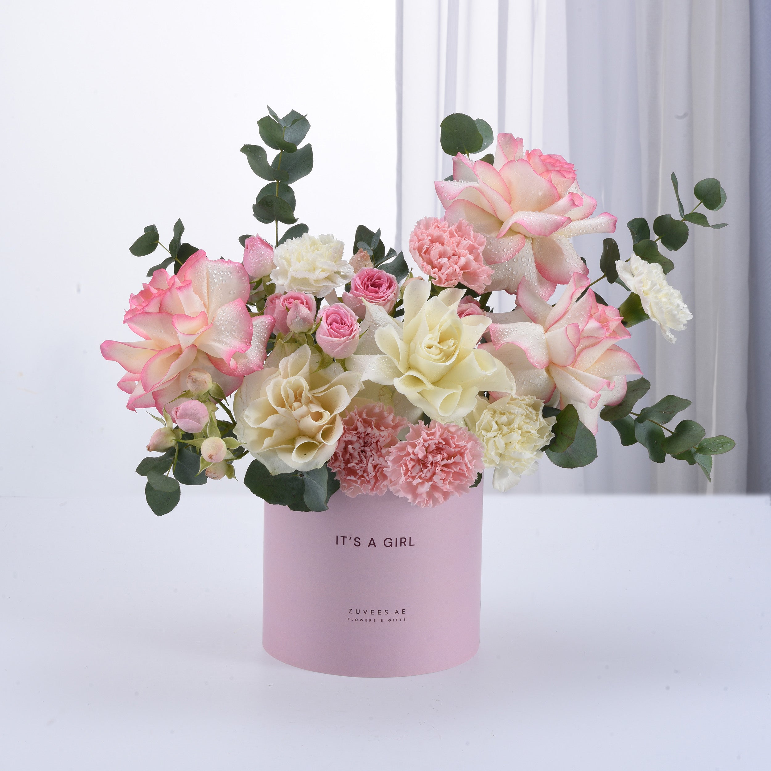 Soft pink and white roses, carnations, and eucalyptus in a pastel pink "It&