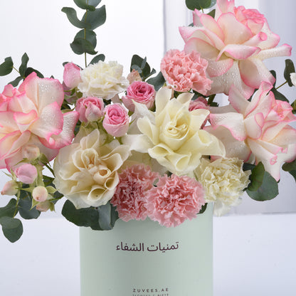 Pastel pink and cream roses, carnations, and eucalyptus in mint vase.