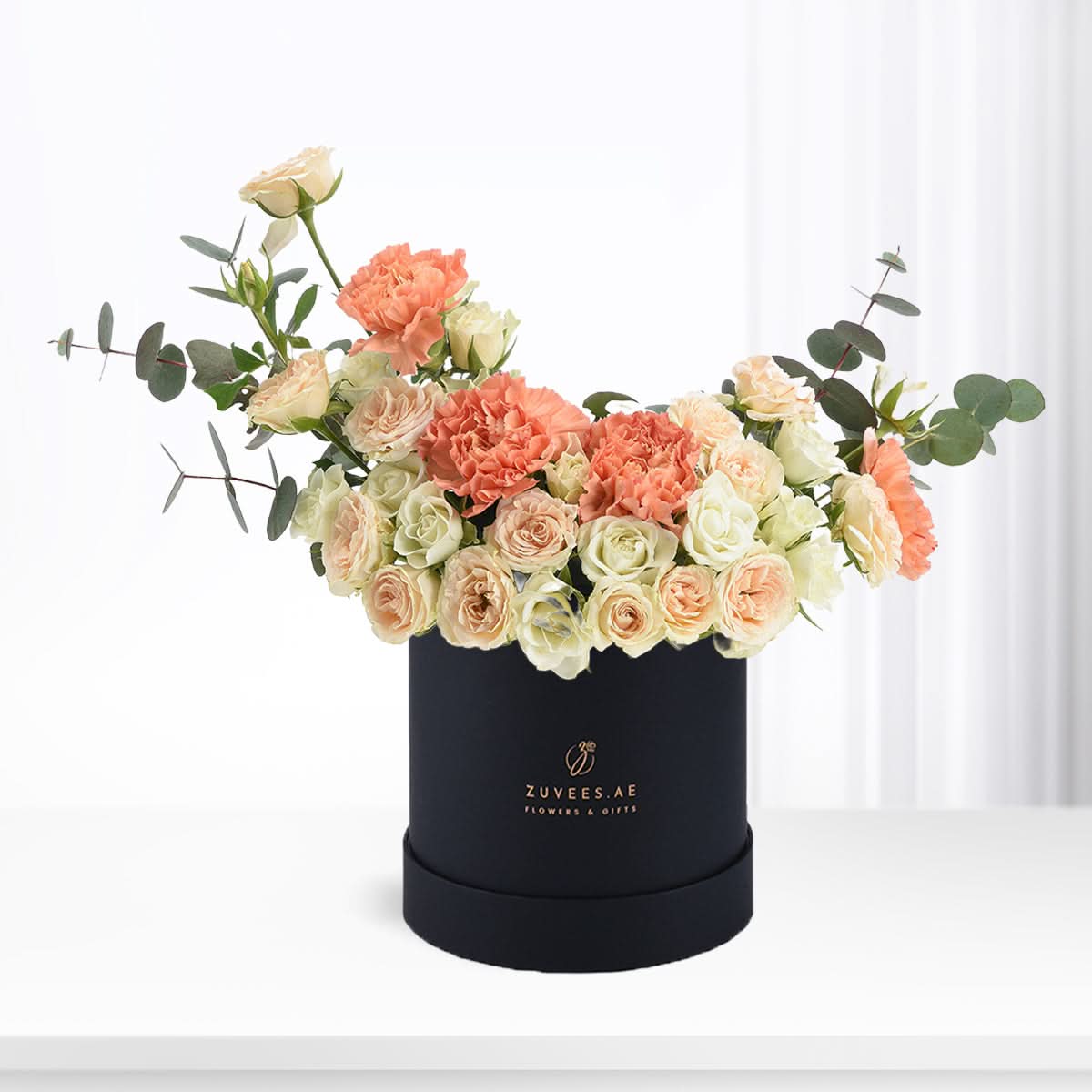 Elegant peach roses and carnations in sleek black box with gold logo.