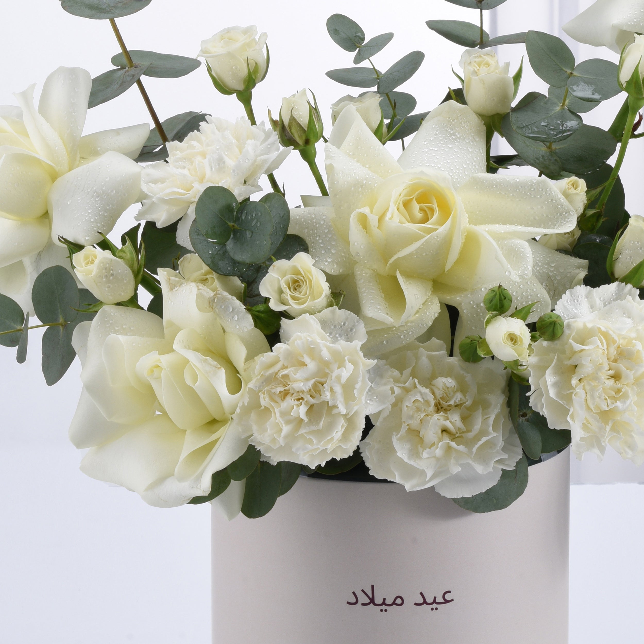 White roses and carnations with dewdrops in minimalist vase.