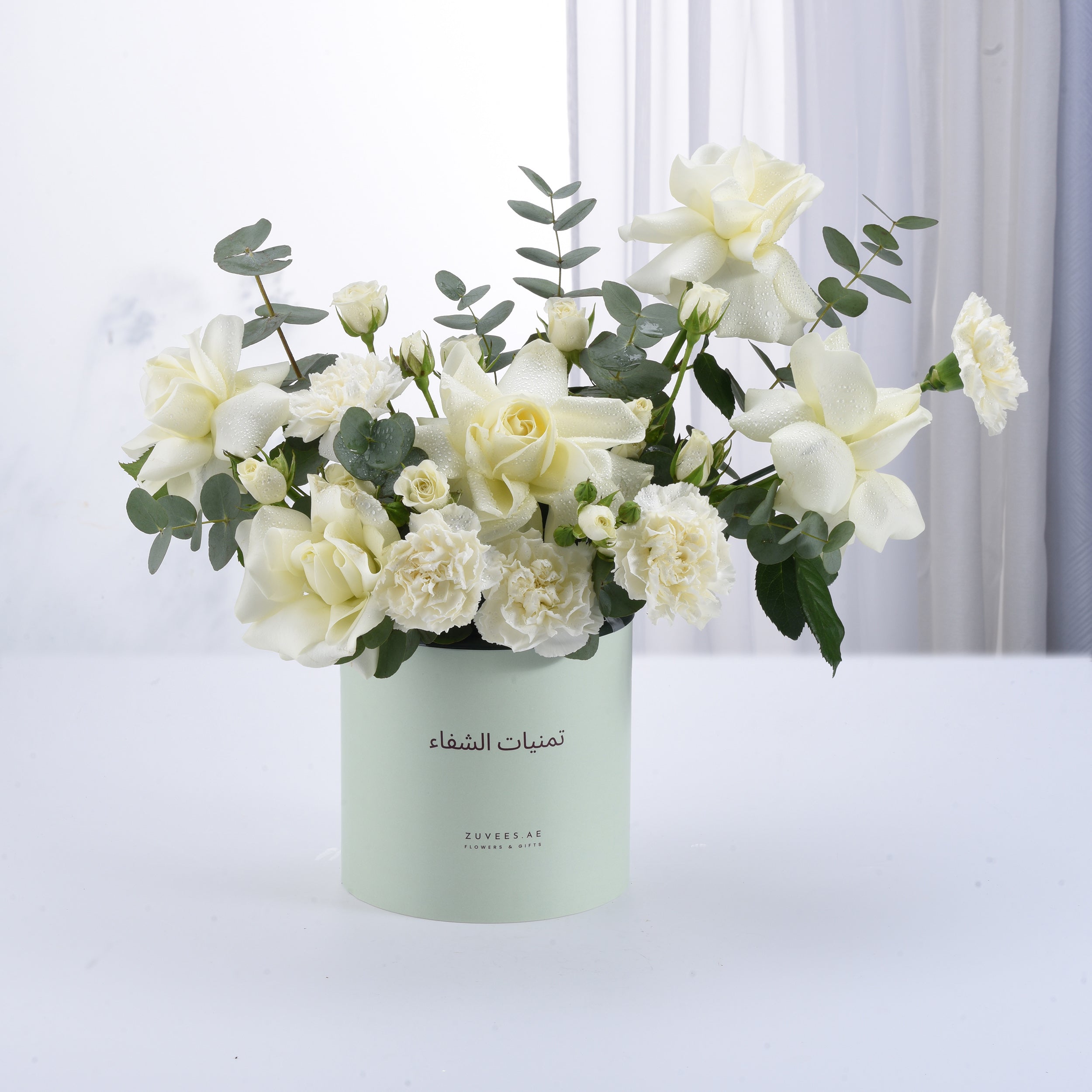 Elegant white roses and carnations in mint-green cylindrical gift box.