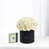 Elegant ivory roses in matte black hat box beside green Patchi gift box.