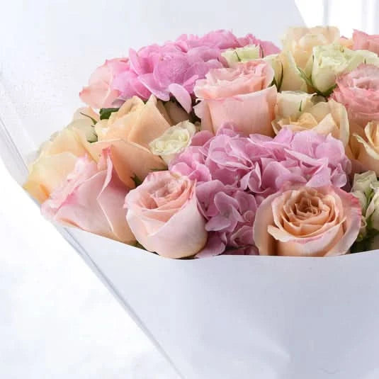 Soft pink roses and hydrangeas in elegant white wrap.