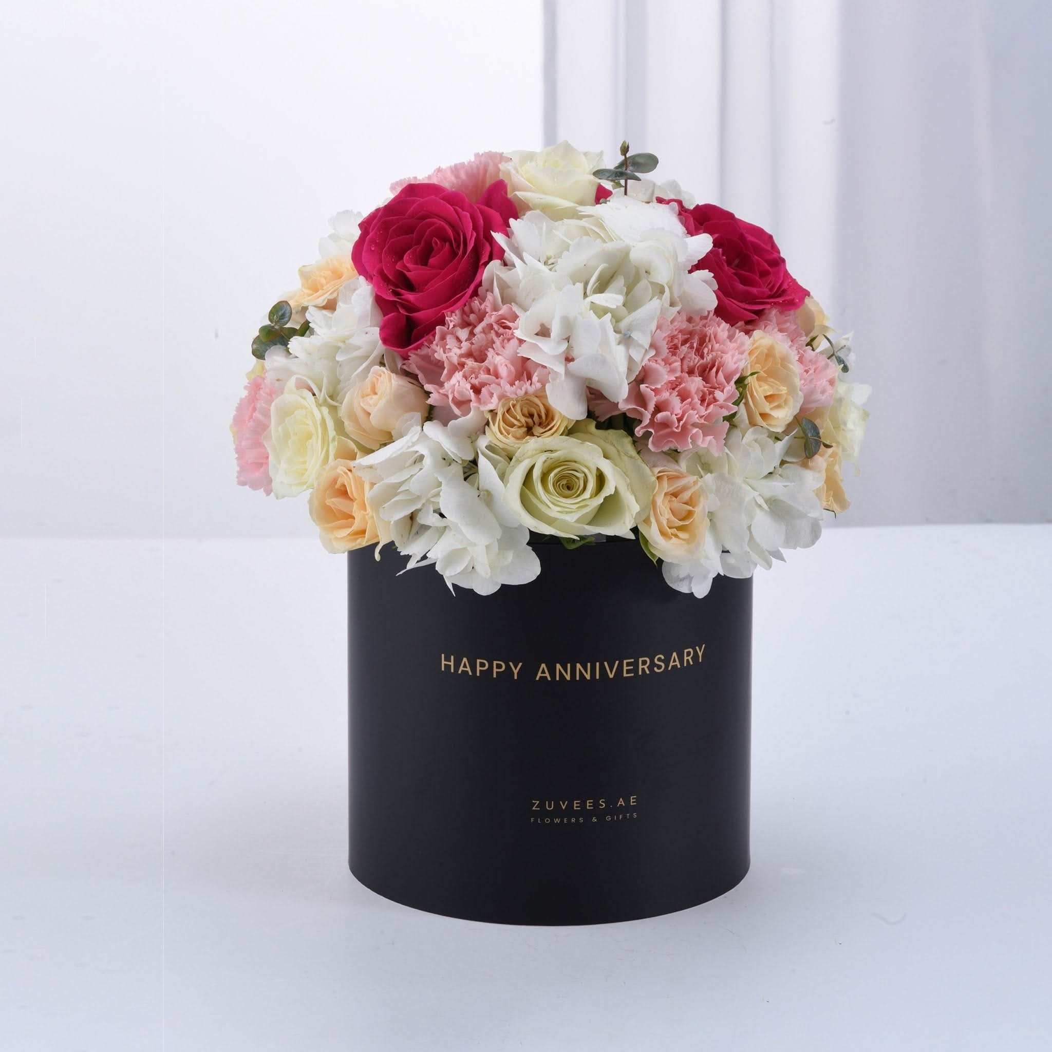 Elegant black box filled with vibrant pink, white, and cream roses and hydrangeas, celebrating anniversary.
