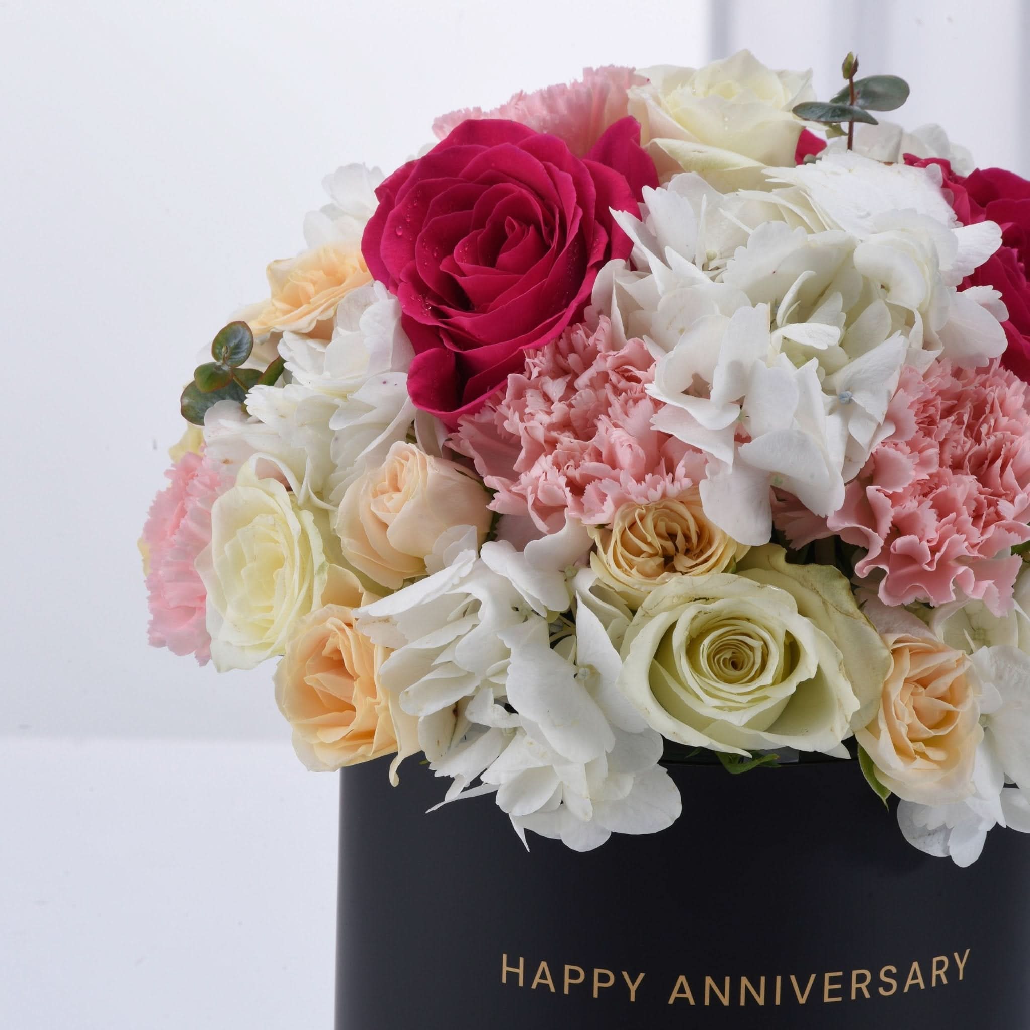 Vibrant pink, white, and peach roses and hydrangeas in black "Happy Anniversary" box.
