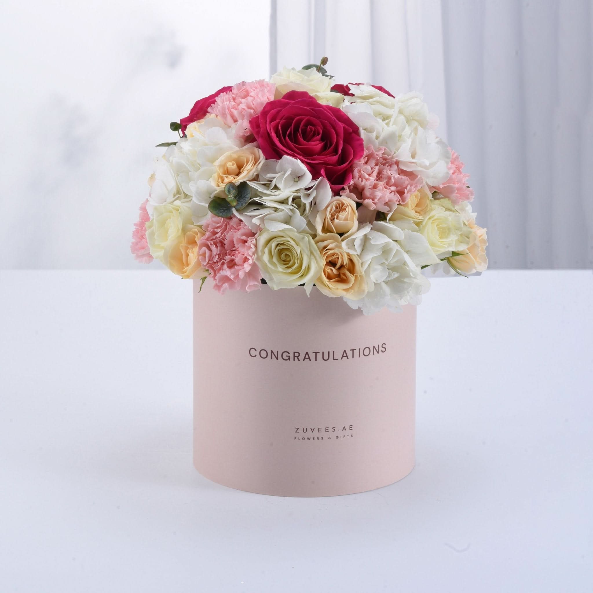 Pink box with "CONGRATULATIONS" holds vibrant roses, carnations, and hydrangeas.