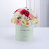 Pastel mint box holds vibrant pink, white, and peach roses and carnations for get-well wishes.