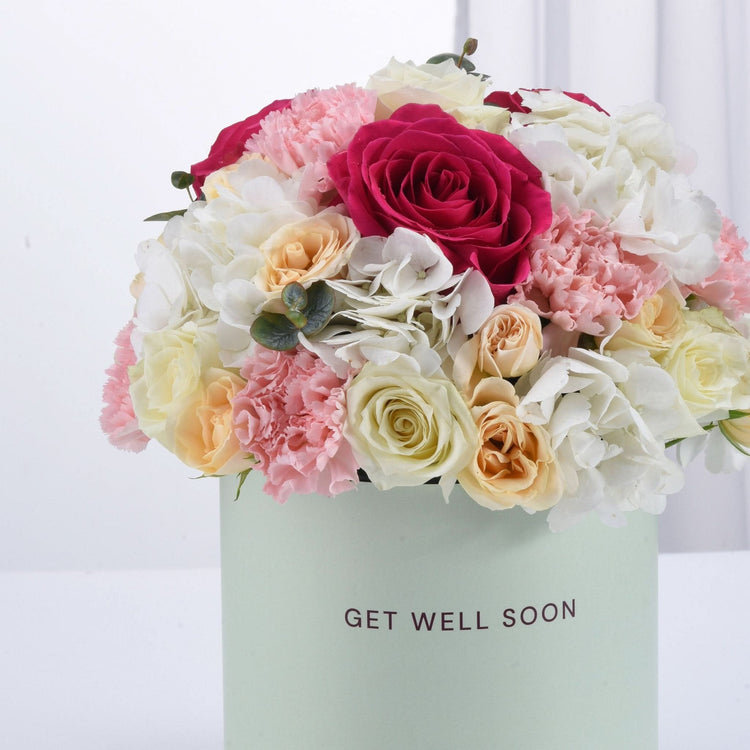 Pastel box holds vibrant roses, carnations, and hydrangeas—perfect "Get Well Soon" gift.