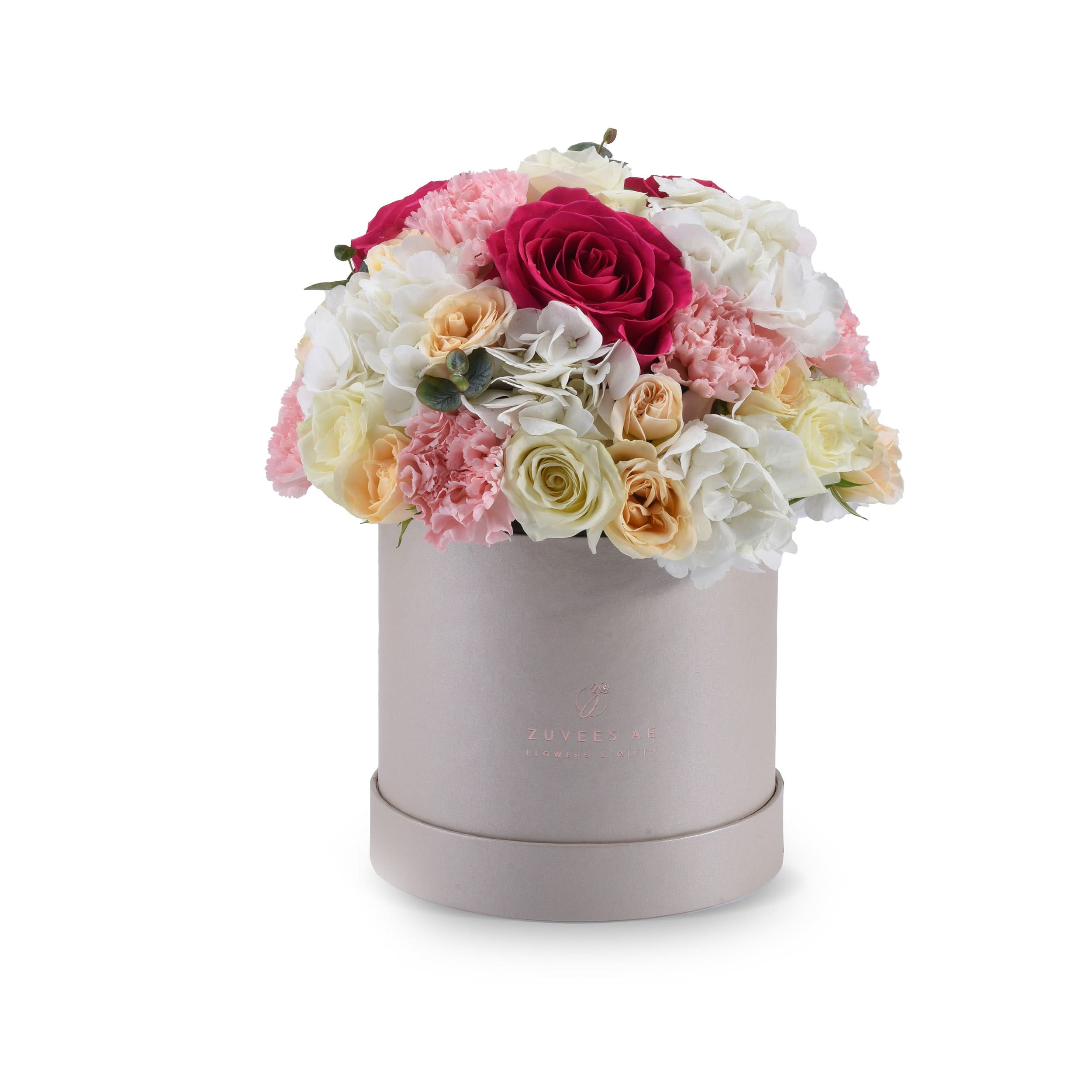 Elegant pastel floral arrangement in matte silver hat box with branded logo.