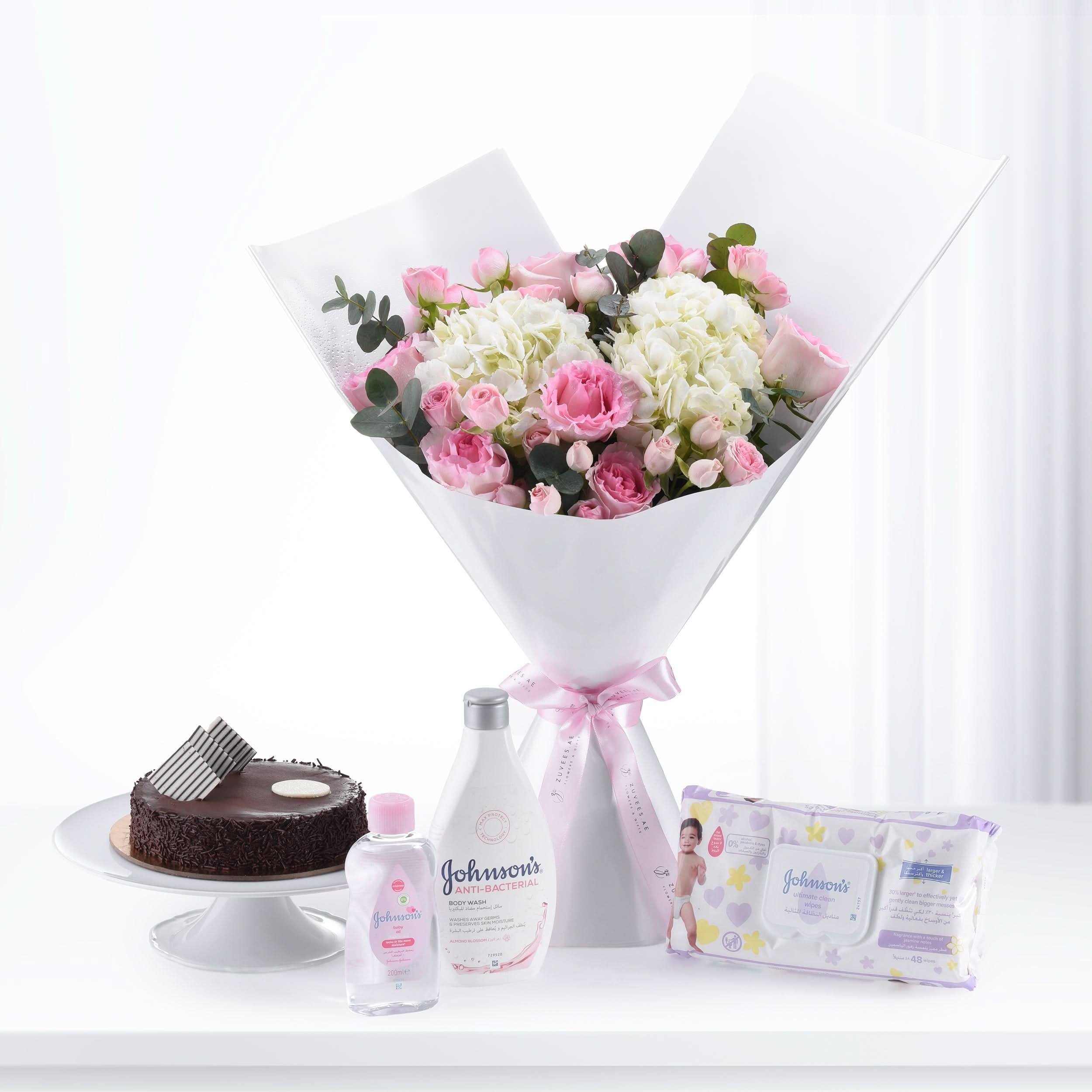 Pink roses and hydrangeas bouquet with chocolate cake and Johnson’s baby care products.