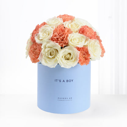 Pastel blue box holds creamy white roses and coral carnations, celebrating "It&