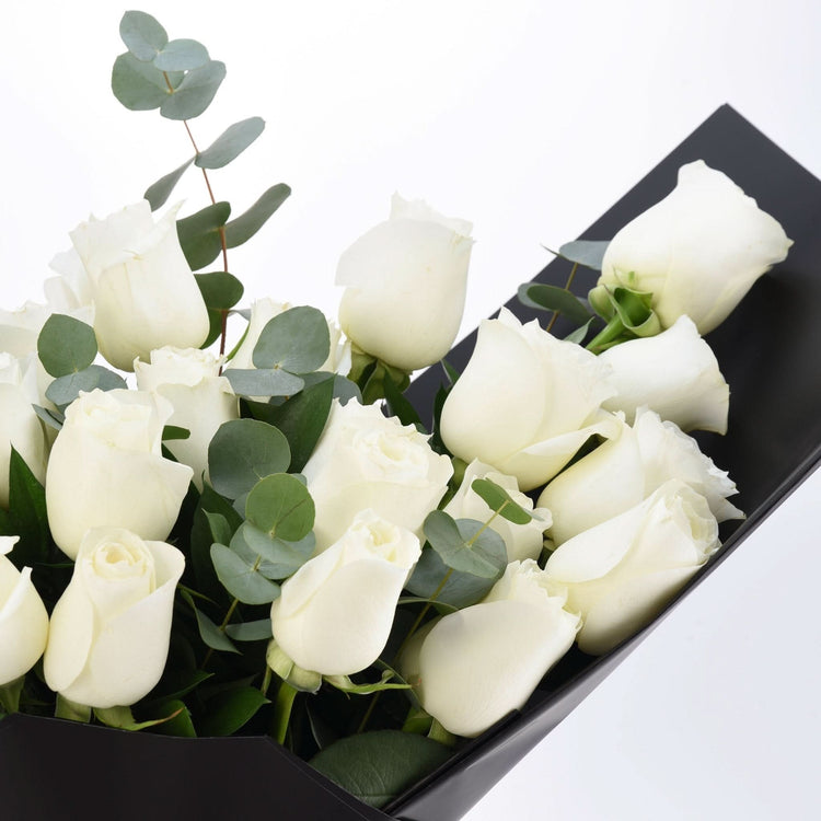 Elegant white roses with eucalyptus, nestled in sleek black wrapping.