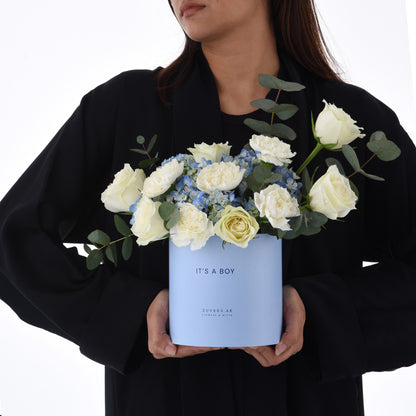 Light blue box holds white roses and hydrangeas, “It’s a Boy” gift.