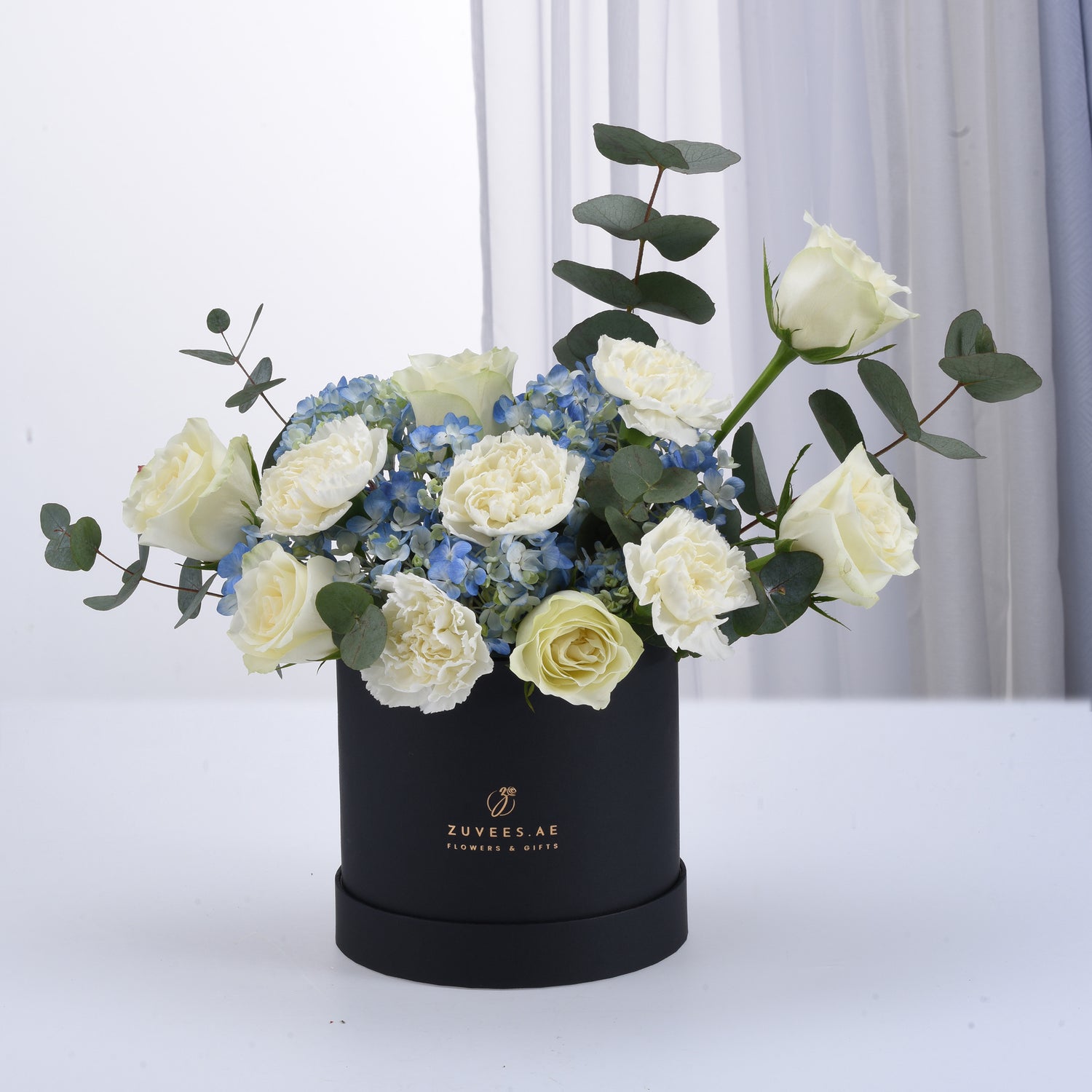Elegant white roses and blue hydrangeas in matte black box.