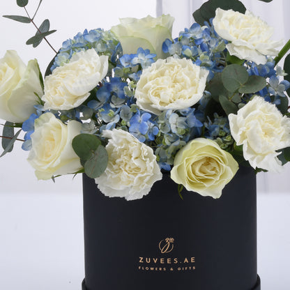 Elegant white roses and blue hydrangeas in sleek black gift box.