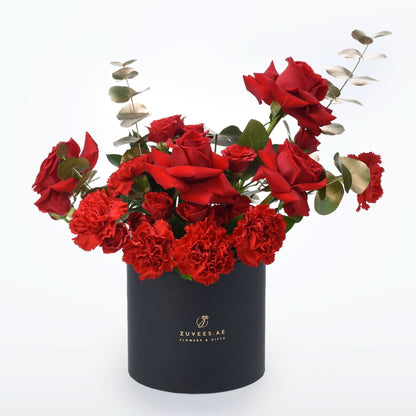 Vibrant red roses and carnations in sleek black Zuvees box, accented with silver eucalyptus.