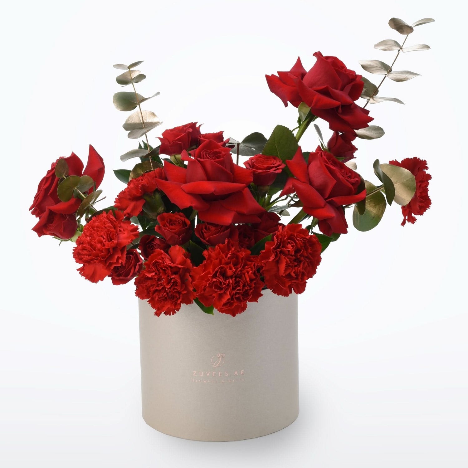 Vibrant red roses and carnations in elegant beige cylindrical vase.
