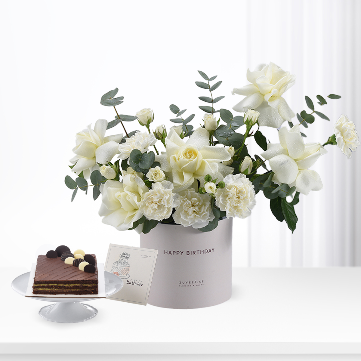 Elegant white roses and eucalyptus in branded box, paired with chocolate cake.