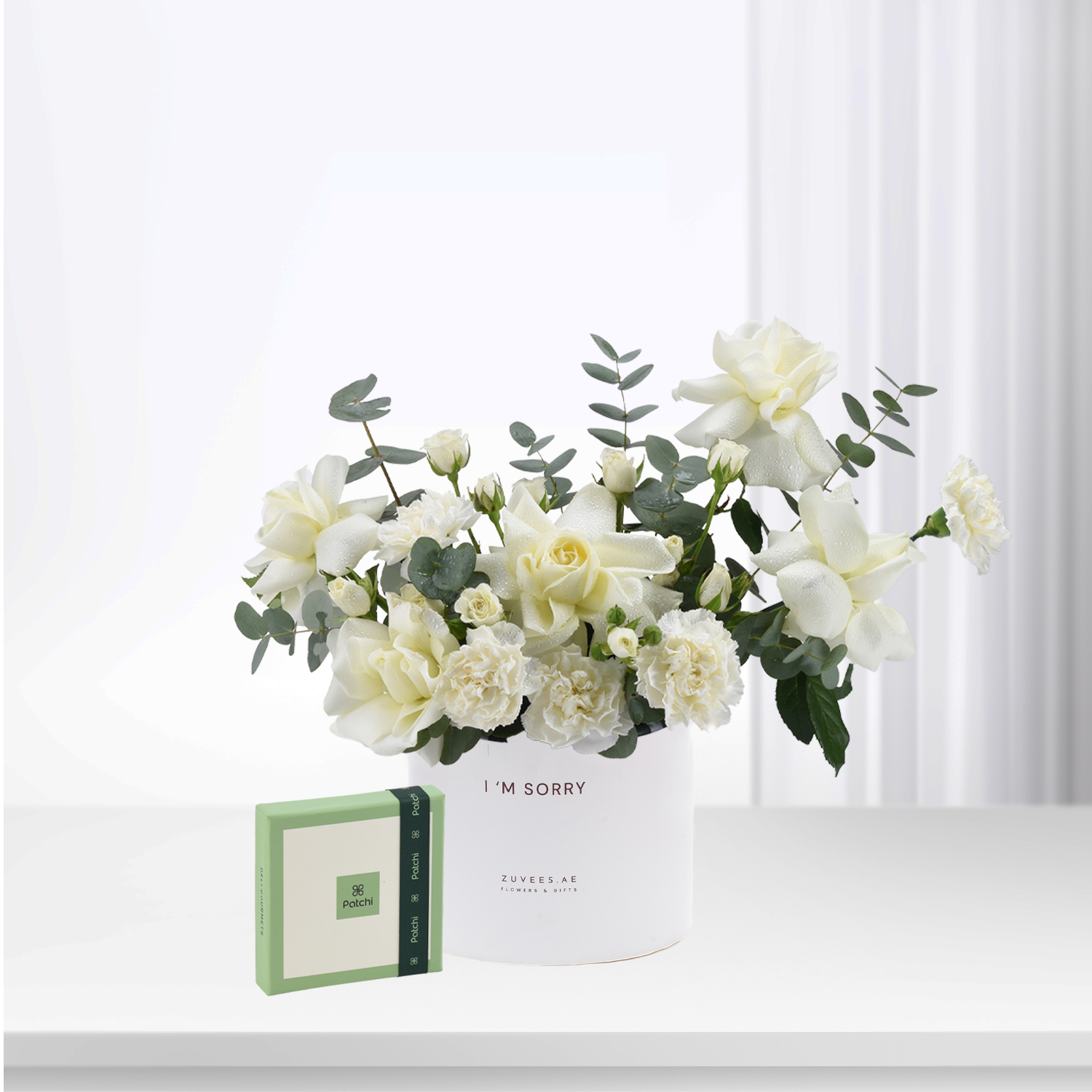 White roses and eucalyptus in minimalist white vase with “I&