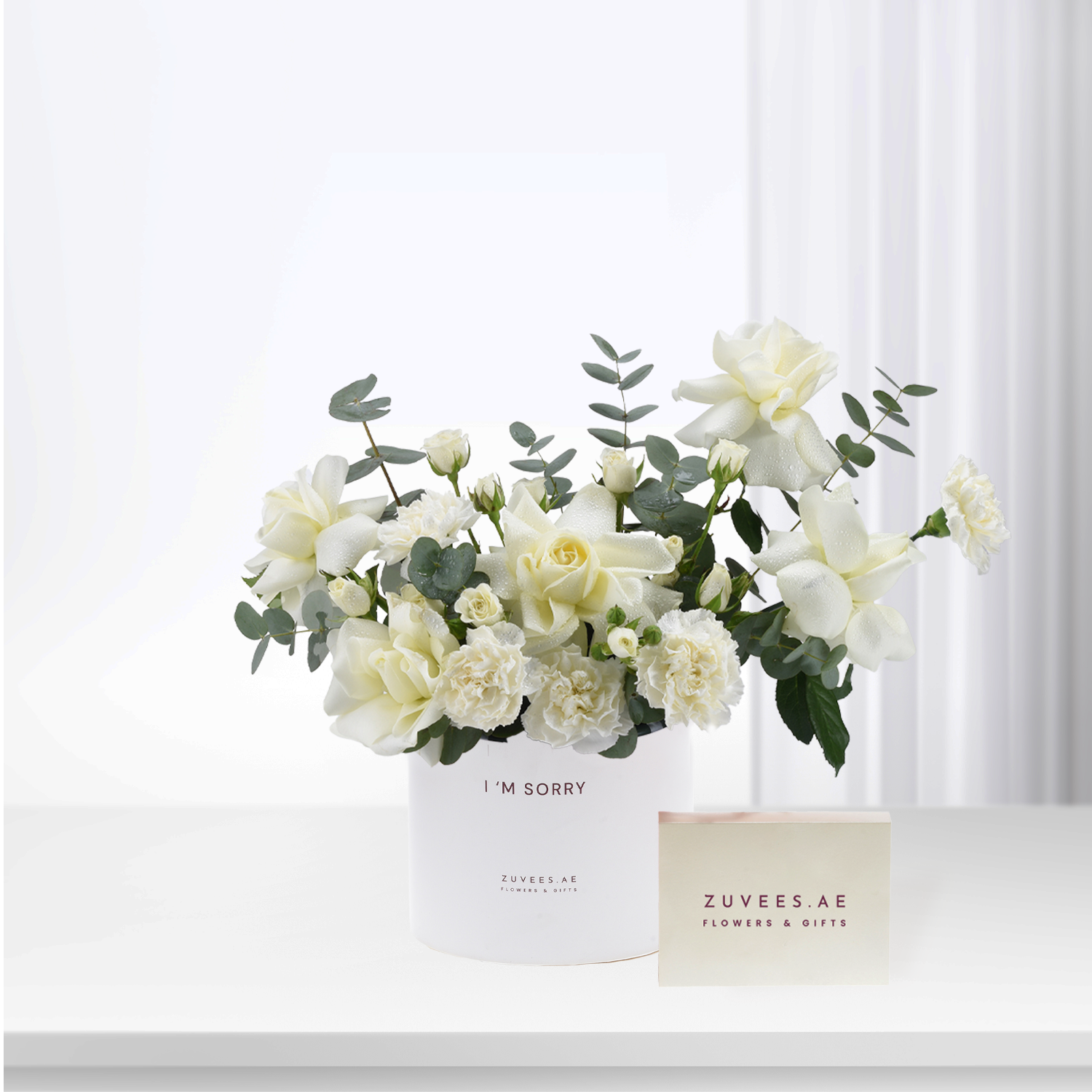 White roses and eucalyptus in minimalist white vase with “I&