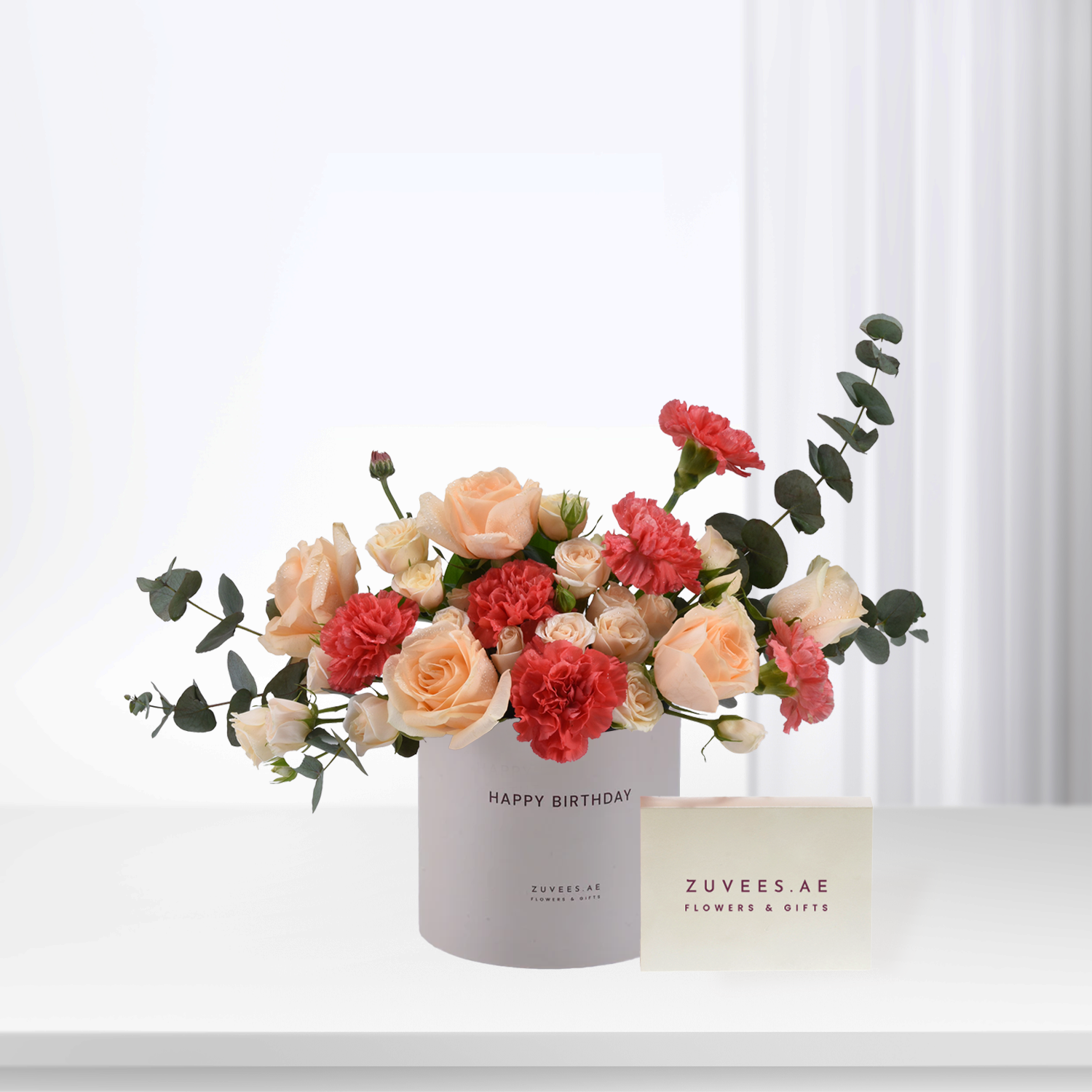 Soft peach roses and red carnations in white "Happy Birthday" box with eucalyptus.