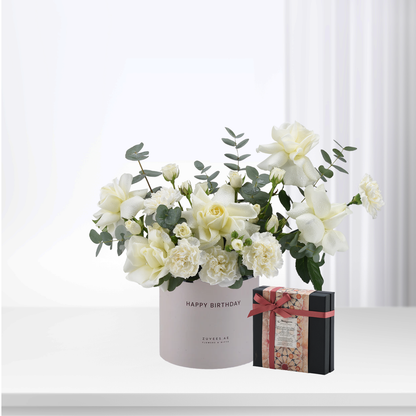White roses and eucalyptus in "Happy Birthday" box with chocolate gift.