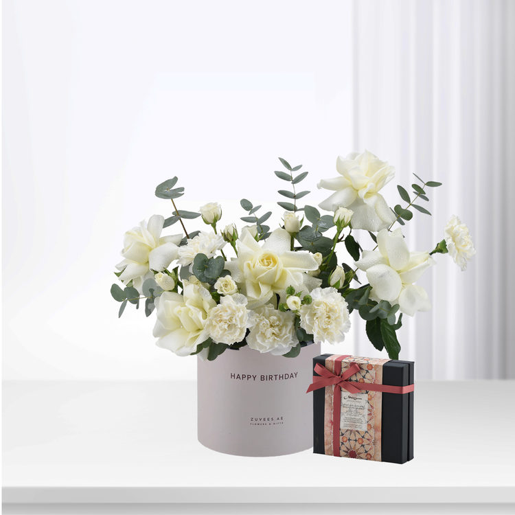 White roses and eucalyptus in "Happy Birthday" box with chocolate gift.