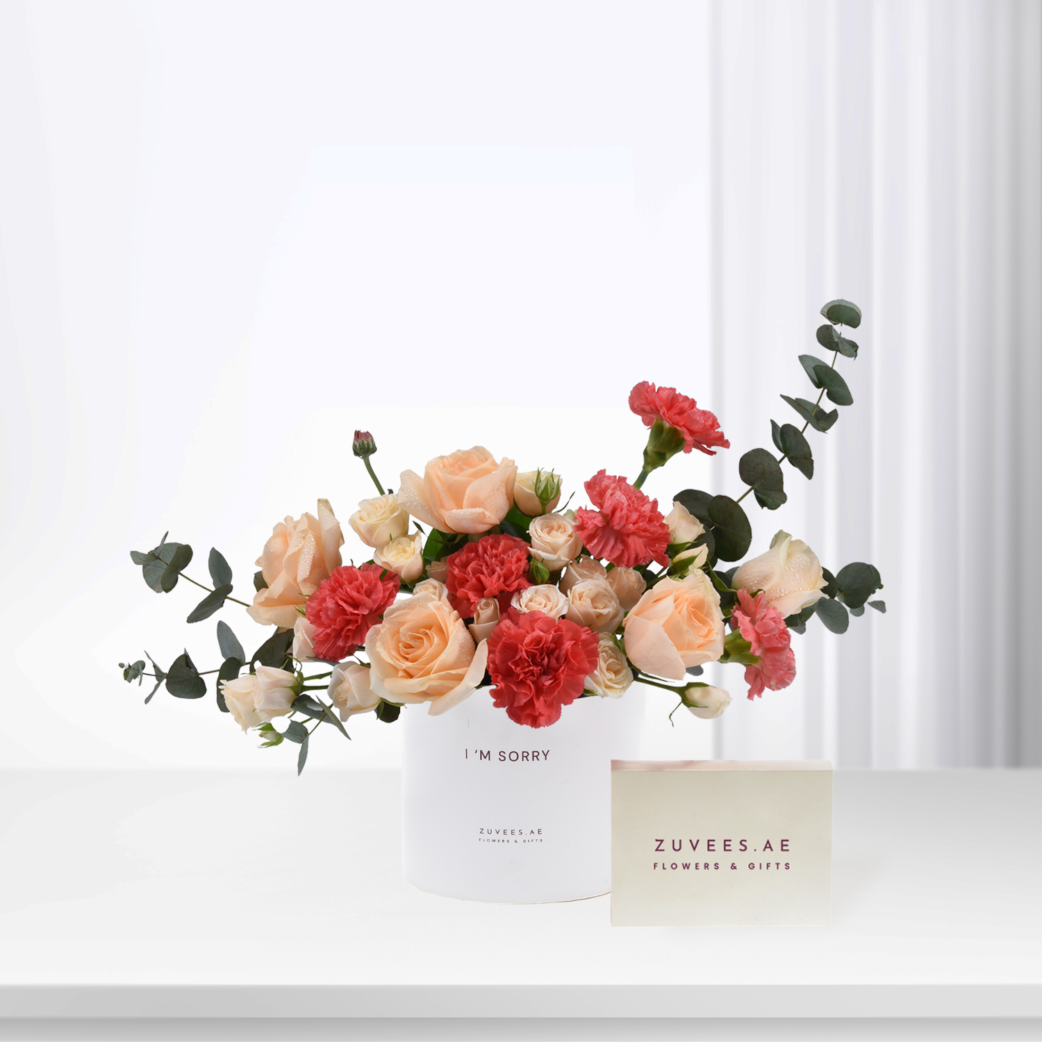 Soft peach roses and red carnations in white vase with “I’m Sorry” message.