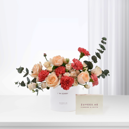 Soft peach roses and red carnations in white vase with “I’m Sorry” message.