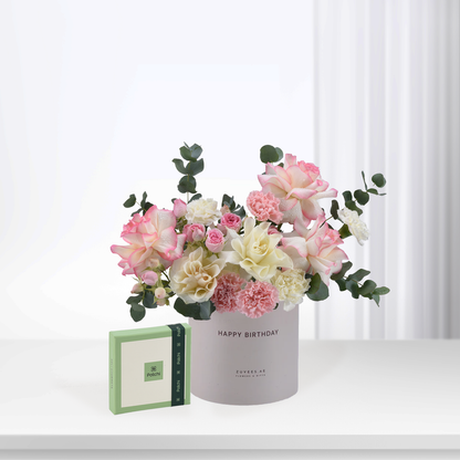 Soft pink, white roses and carnations in gray "Happy Birthday" vase with Patchi gift box.