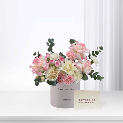 Soft pink and cream roses with eucalyptus in branded birthday vase.