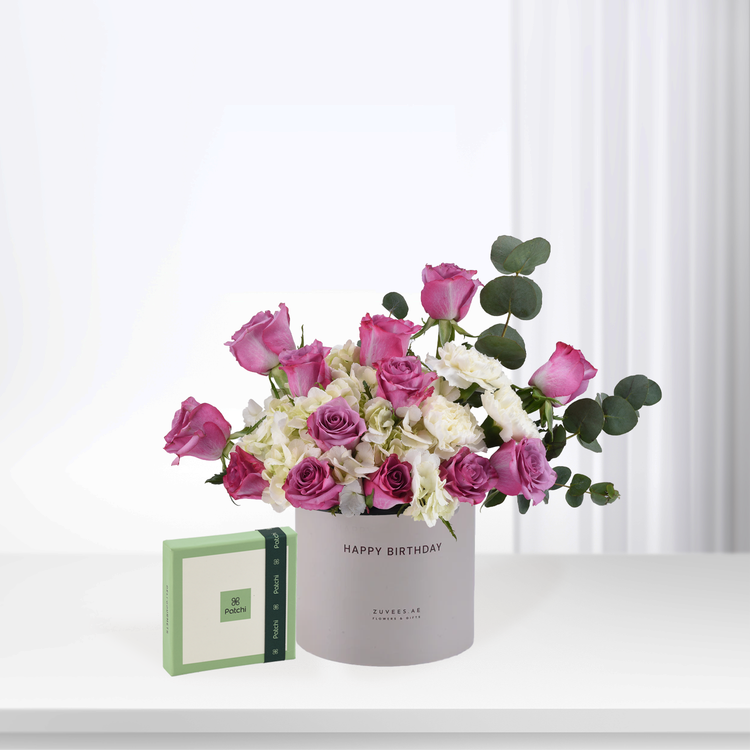 Pink roses, white hydrangeas, and eucalyptus in gray "Happy Birthday" box with Patchi chocolate gift.